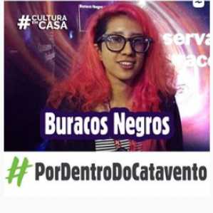 Foto de uma mulher com cabelo rosa e óculos sorrindo. Ao fundo algumas luzes em formato circular