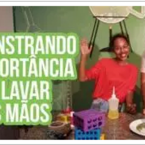 Na foto um casal com alguns itens de laboratório sorriem para a foto. Na lateral da foto escrito: "Demonstrando a importância de lavar as mãos"