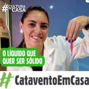 Foto de uma mulher de jaleco branco sorrindo e segurando um objeto rosa