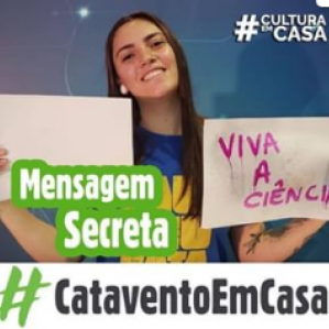 Foto de uma mulher sorrindo com camiseta azul segurando dois papéis