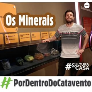 Homem com camiseta cinza sorrindo ao lado de algumas rochas