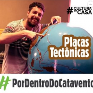 Foto de um homem de camiseta rosa apontando para uma maquete de globo terrestre
