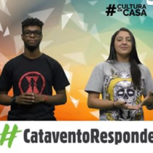 Um homem de camiseta preta e uma mulher com camiseta cinza. Ao fundo um cenário colorido.
