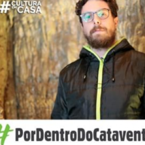 Homem de roupa preta e óculos. Ao fundo caverna artificial do Museu Catavento