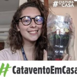 Foto de uma mulher de óculos sorrindo segurando uma garrafa pet