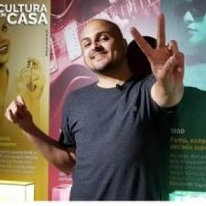 Homem careca sorrindo fazendo um v com as mãos