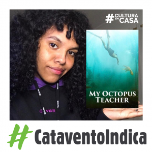 Mulher com cabelos cacheados, ao lado direito a capa do filme