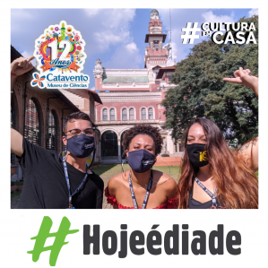 Um homem e duas mulheres com máscaras e ao fundo o palácio das indústrias