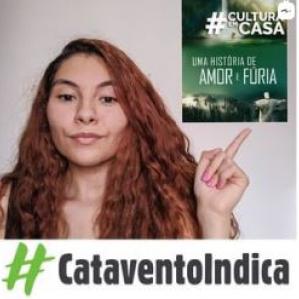 Mulher de cabelos cacheados ruivos, sorrindo e apontando para a capa no filme 
